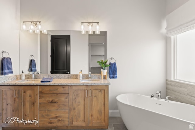 bathroom featuring a freestanding tub, double vanity, a sink, and tile patterned flooring