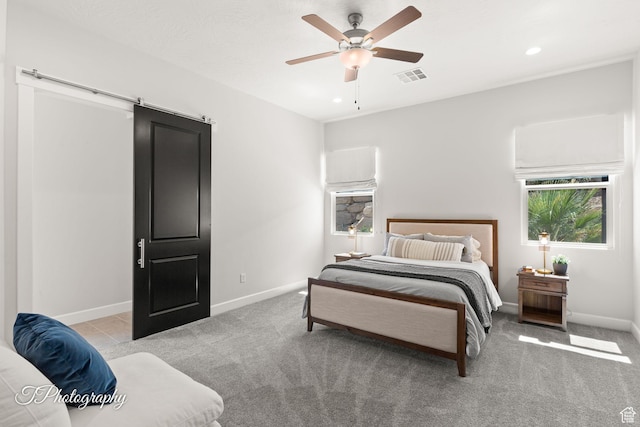 carpeted bedroom featuring baseboards, a ceiling fan, visible vents, and a barn door