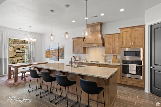 kitchen featuring custom range hood, backsplash, visible vents, wood tiled floor, and appliances with stainless steel finishes