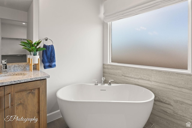full bath with a soaking tub, vanity, and tile walls