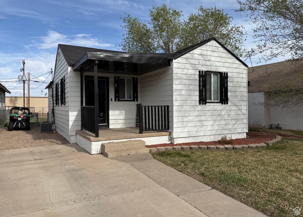 bungalow-style house with a porch, central air condition unit, and a front lawn