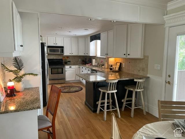 506 S 1200 E, Bountiful, UT 84010 - kitchen featuring appliances with stainless steel finishes, a peninsula, plenty of natural light, white cabinets, and crown molding