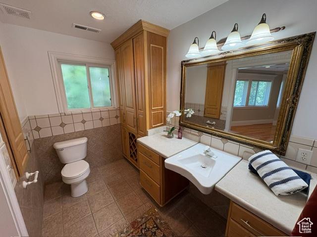 506 S 1200 E, Bountiful, UT 84010 - bathroom featuring toilet, tile patterned flooring, tile walls, and a sink