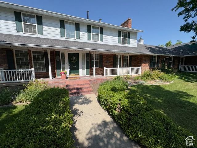 506 S 1200 E, Bountiful, UT 84010 - view of front of property featuring a porch, a chimney, a front lawn, and brick siding