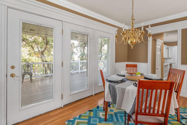 506 S 1200 E, Bountiful, UT 84010 - dining space with crown molding, a decorative wall, light wood-style flooring, a wainscoted wall, and a chandelier