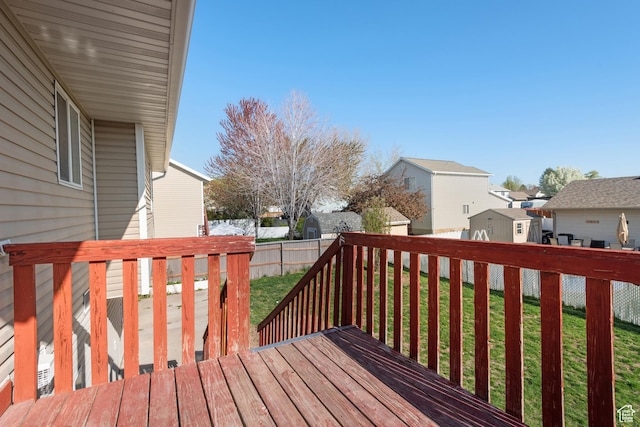 wooden terrace with fence, a residential view, and a lawn