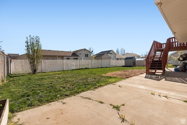 view of yard with a storage shed, a fenced backyard, an outdoor structure, a patio, and stairs