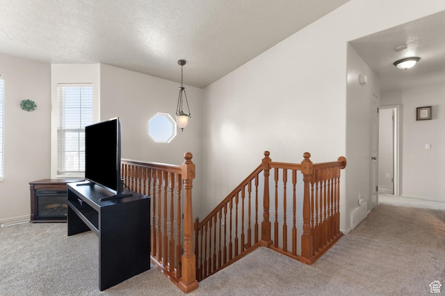 staircase with baseboards, carpet flooring, and a textured ceiling
