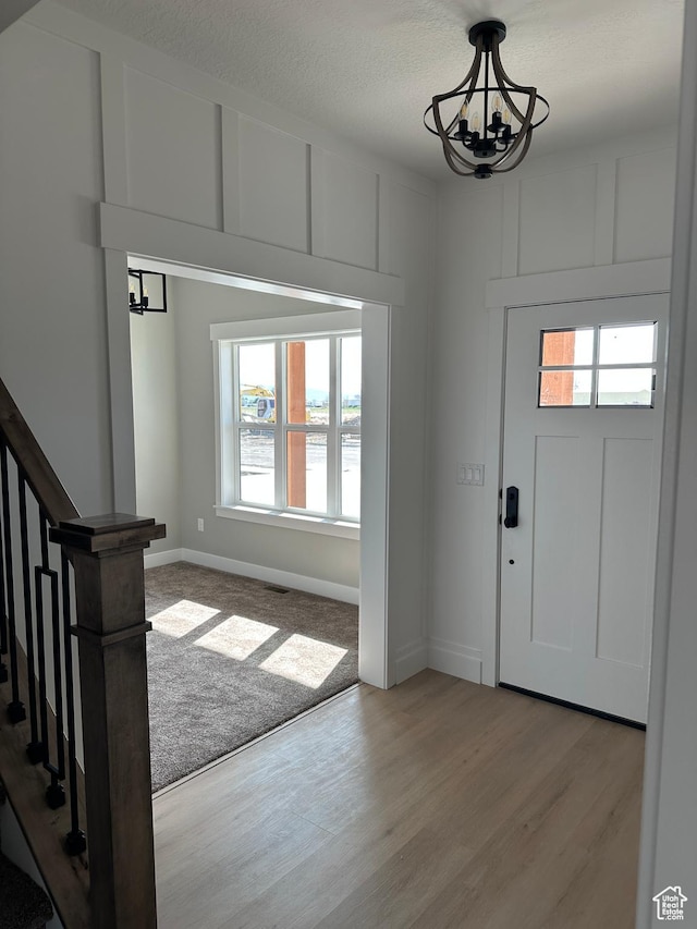 foyer entrance with wood finished floors, an inviting chandelier, and a wealth of natural light