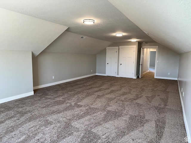 bonus room featuring lofted ceiling, a textured ceiling, baseboards, and carpet floors