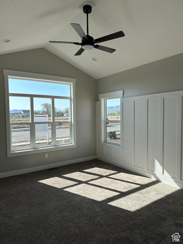 unfurnished bedroom with ceiling fan, multiple windows, carpet, and lofted ceiling