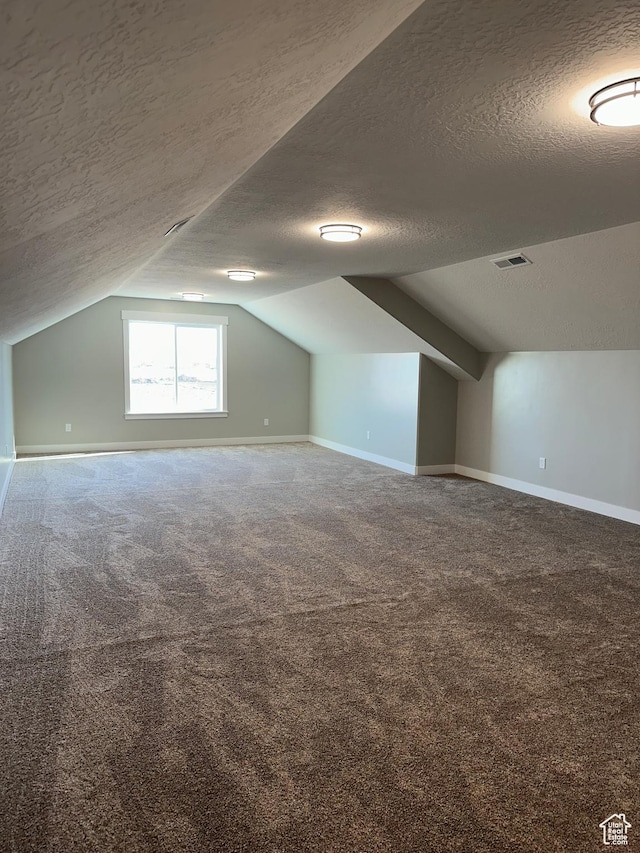 bonus room with a textured ceiling, carpet flooring, baseboards, and visible vents