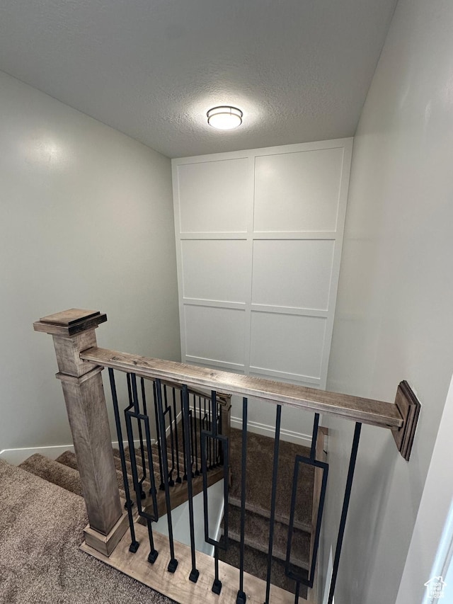 stairs with baseboards, carpet, and a textured ceiling