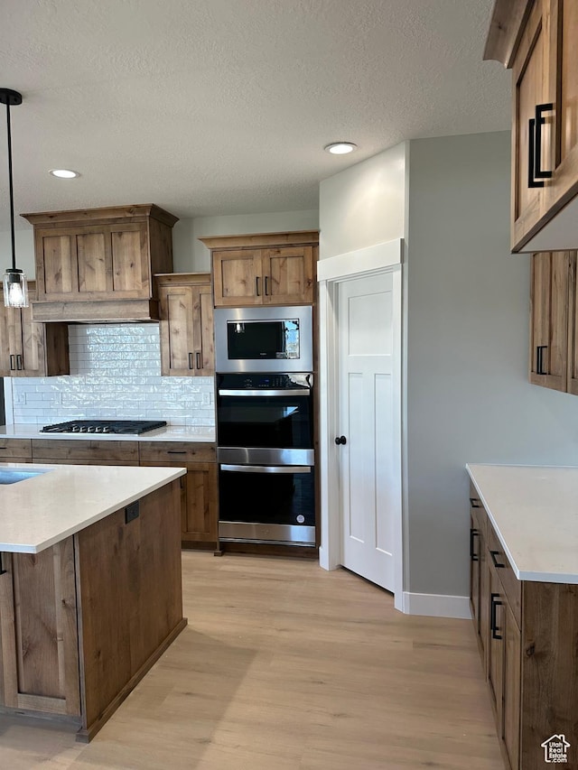 kitchen with light wood-type flooring, light countertops, gas cooktop, built in microwave, and double oven