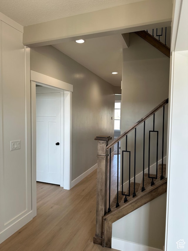 stairs with wood finished floors, baseboards, and recessed lighting