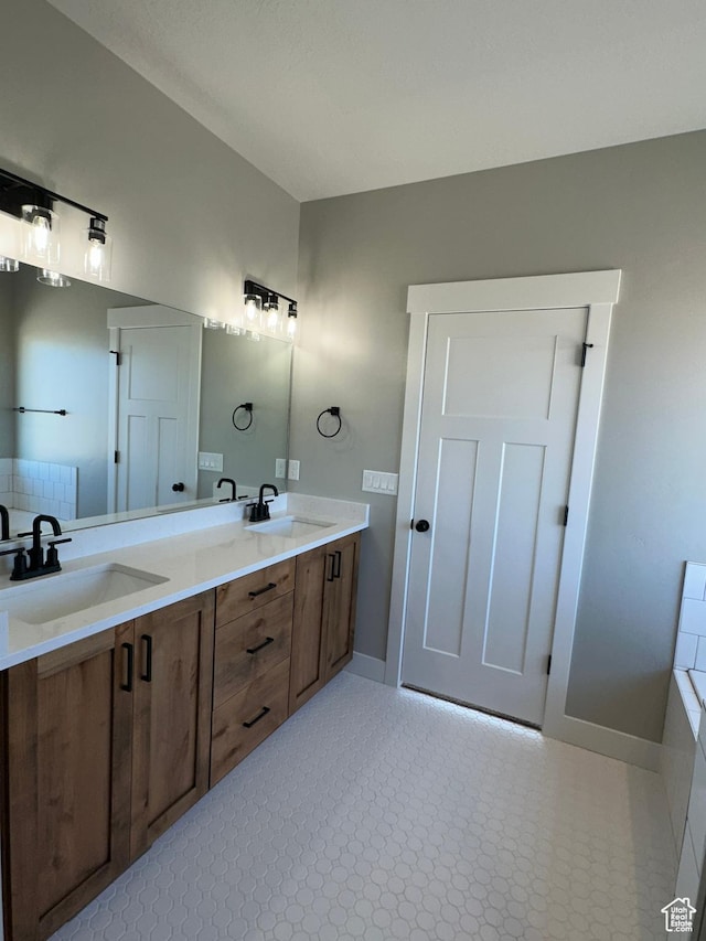 bathroom with double vanity, baseboards, and a sink