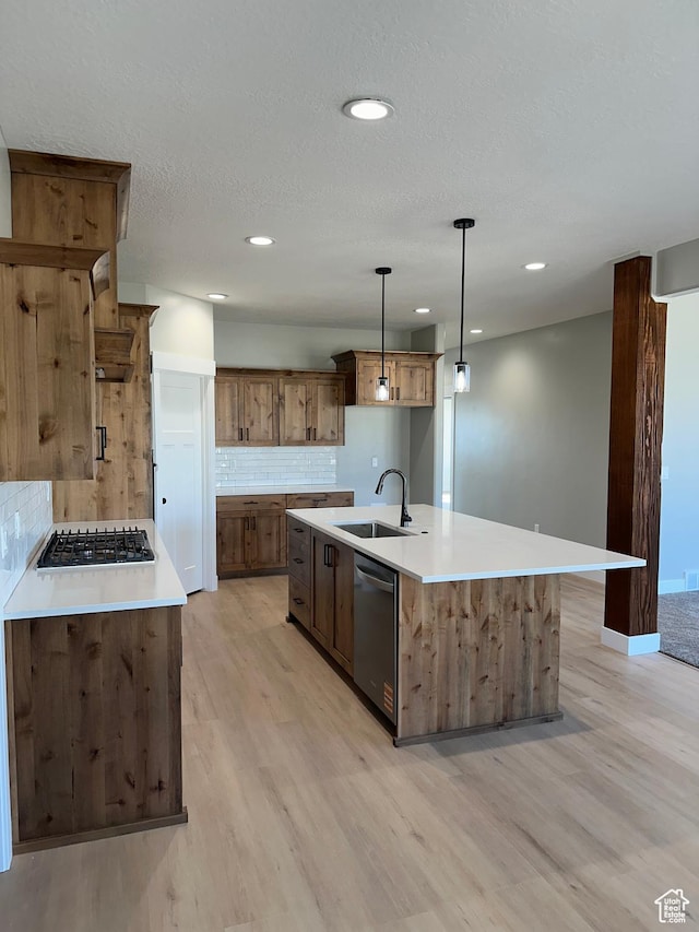 kitchen with tasteful backsplash, gas cooktop, stainless steel dishwasher, light wood finished floors, and a sink