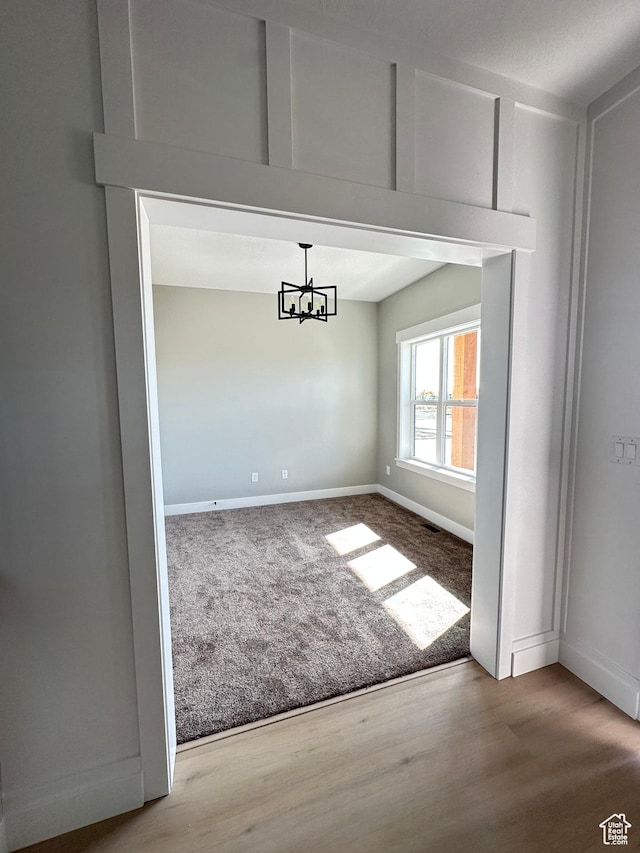 unfurnished dining area featuring visible vents, baseboards, a chandelier, wood finished floors, and carpet flooring