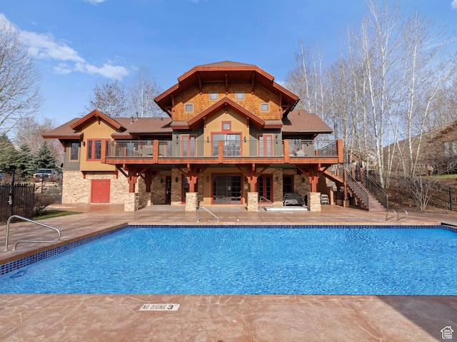back of house with a fenced in pool, stairway, stone siding, a patio area, and a deck