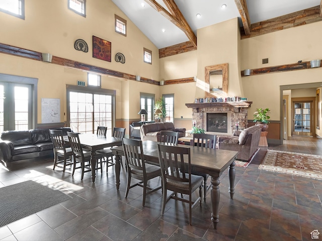 dining space featuring a fireplace, visible vents, plenty of natural light, a high ceiling, and beam ceiling