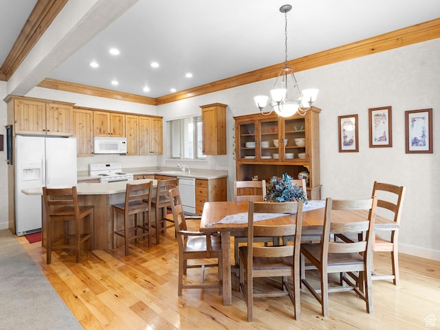 dining space with crown molding, baseboards, light wood finished floors, and a chandelier