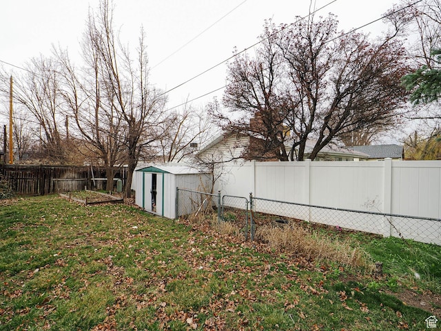 view of yard with a vegetable garden, a fenced backyard, an outdoor structure, and a storage unit