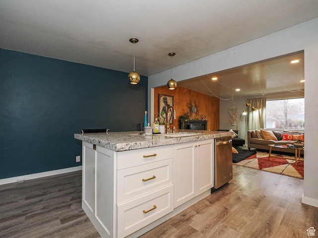 kitchen with decorative light fixtures, a sink, open floor plan, white cabinetry, and wood finished floors