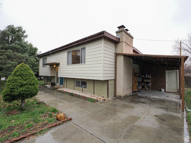 view of front of home featuring concrete driveway, a carport, and a chimney