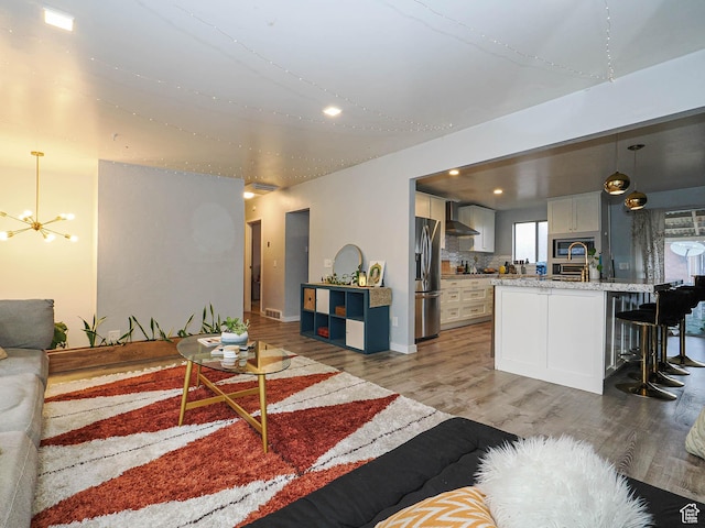 living room featuring visible vents, baseboards, an inviting chandelier, recessed lighting, and light wood-style flooring