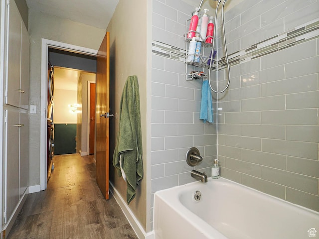 bathroom featuring baseboards, tub / shower combination, and wood finished floors
