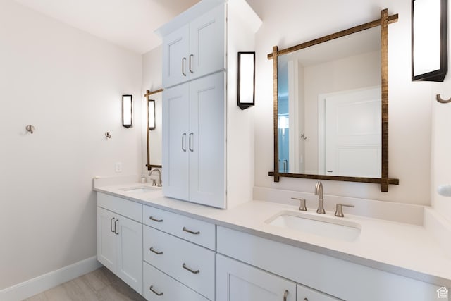bathroom with baseboards, a sink, and double vanity