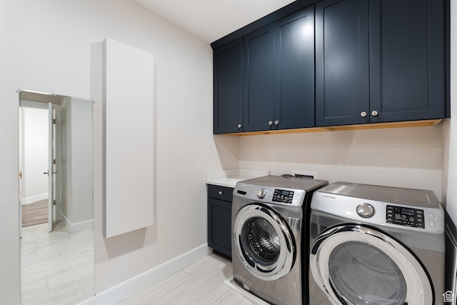 laundry area featuring washing machine and clothes dryer, cabinet space, and baseboards