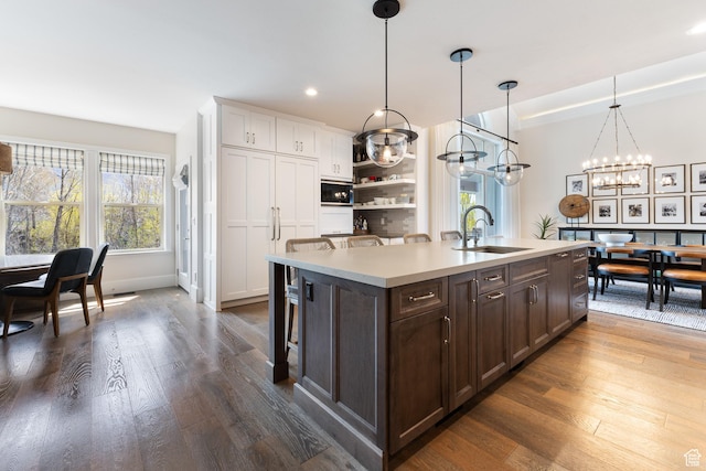 kitchen featuring dark wood-type flooring, dark brown cabinets, light countertops, and a sink