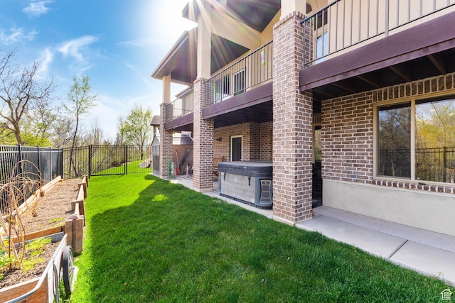 view of yard featuring a hot tub, a fenced backyard, a balcony, and a vegetable garden