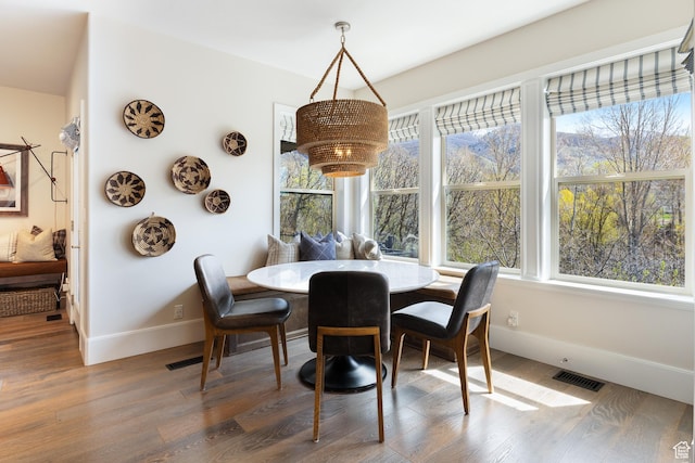 dining area with baseboards, wood finished floors, visible vents, and plenty of natural light