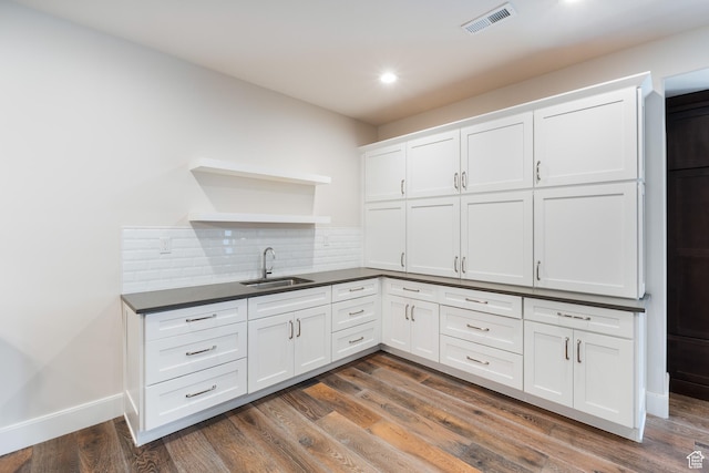 kitchen with open shelves, dark countertops, visible vents, a sink, and decorative backsplash