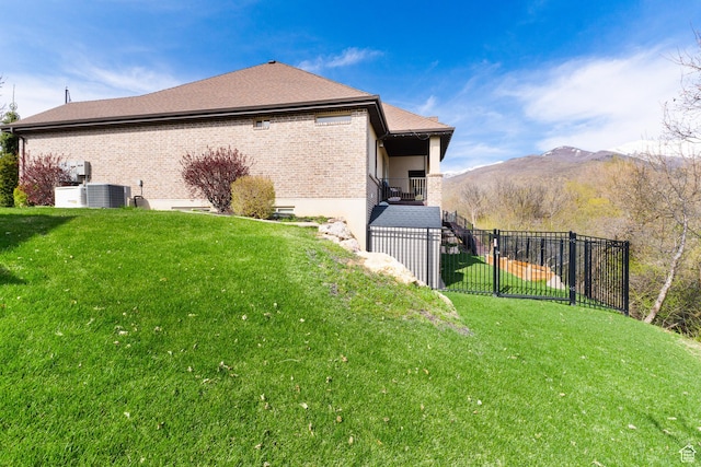 view of home's exterior with fence, a lawn, brick siding, and cooling unit