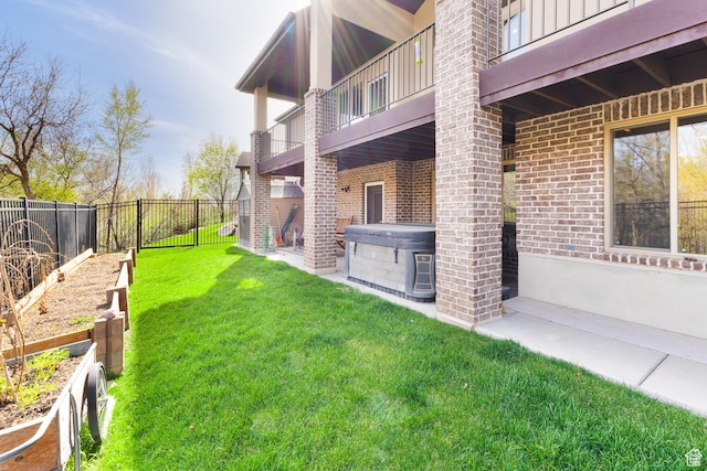 view of yard with a fenced backyard, a garden, a hot tub, and a balcony