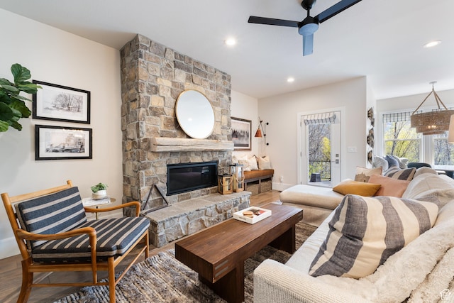 living area with recessed lighting, a stone fireplace, wood finished floors, a ceiling fan, and baseboards
