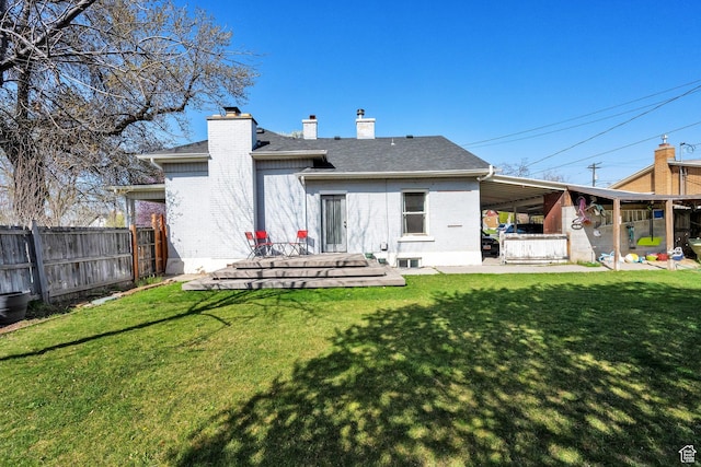 back of house featuring a chimney, a patio area, brick siding, a yard, and fence
