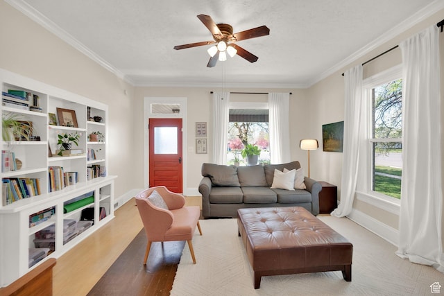 living area with ornamental molding, baseboards, a ceiling fan, and wood finished floors