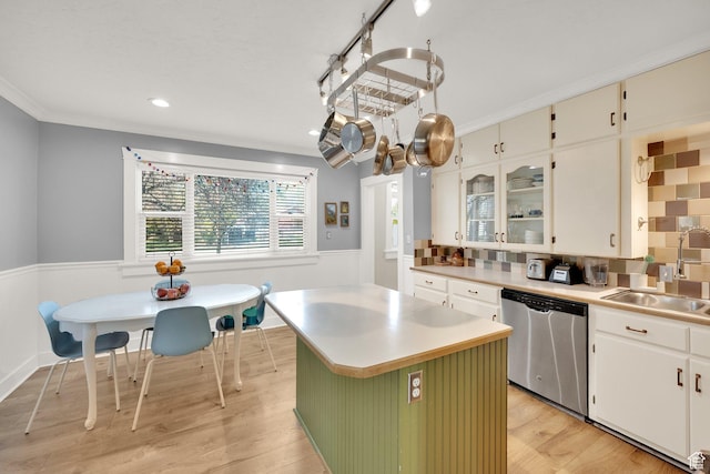kitchen with light wood-style flooring, light countertops, wainscoting, dishwasher, and a sink