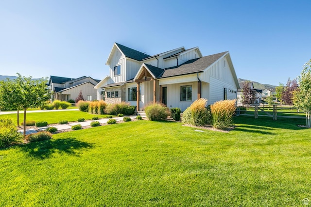 traditional-style house featuring a front yard, board and batten siding, and a shingled roof