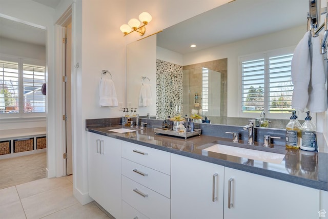 bathroom featuring a shower stall, tile patterned floors, double vanity, and a sink