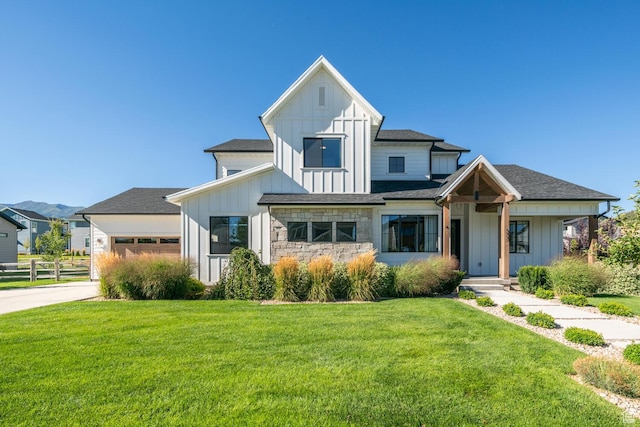 modern inspired farmhouse featuring a front yard, board and batten siding, fence, and an attached garage