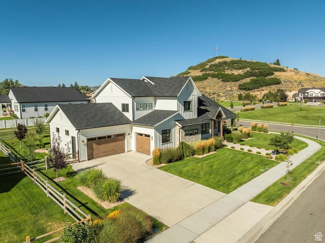 view of front facade featuring an attached garage, board and batten siding, fence, concrete driveway, and a front lawn