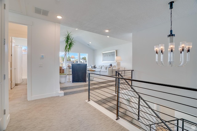 hall with visible vents, baseboards, a notable chandelier, carpet, and vaulted ceiling