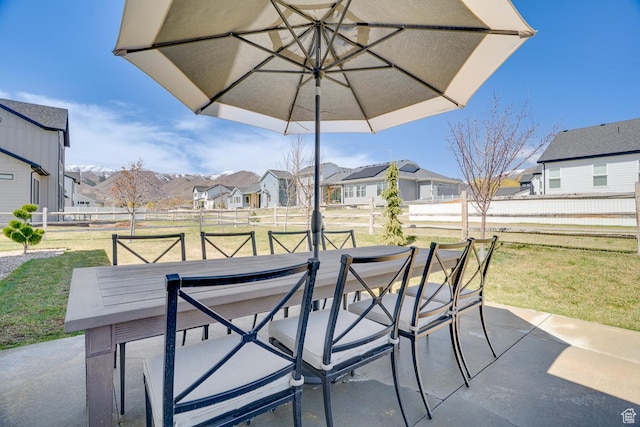 view of patio featuring outdoor dining space, fence, and a residential view