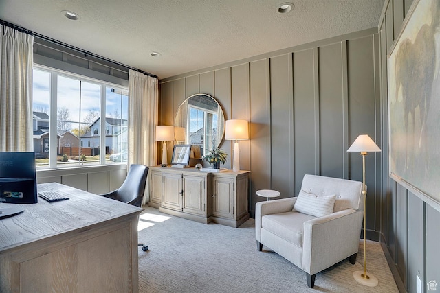 office space featuring light carpet, a decorative wall, a textured ceiling, and recessed lighting