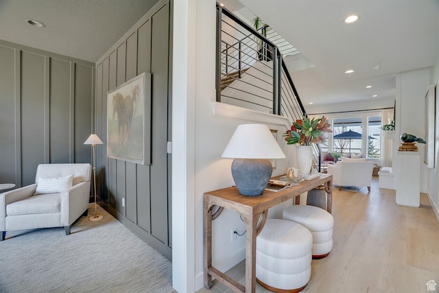 hallway with a decorative wall, light wood-style floors, stairway, and recessed lighting